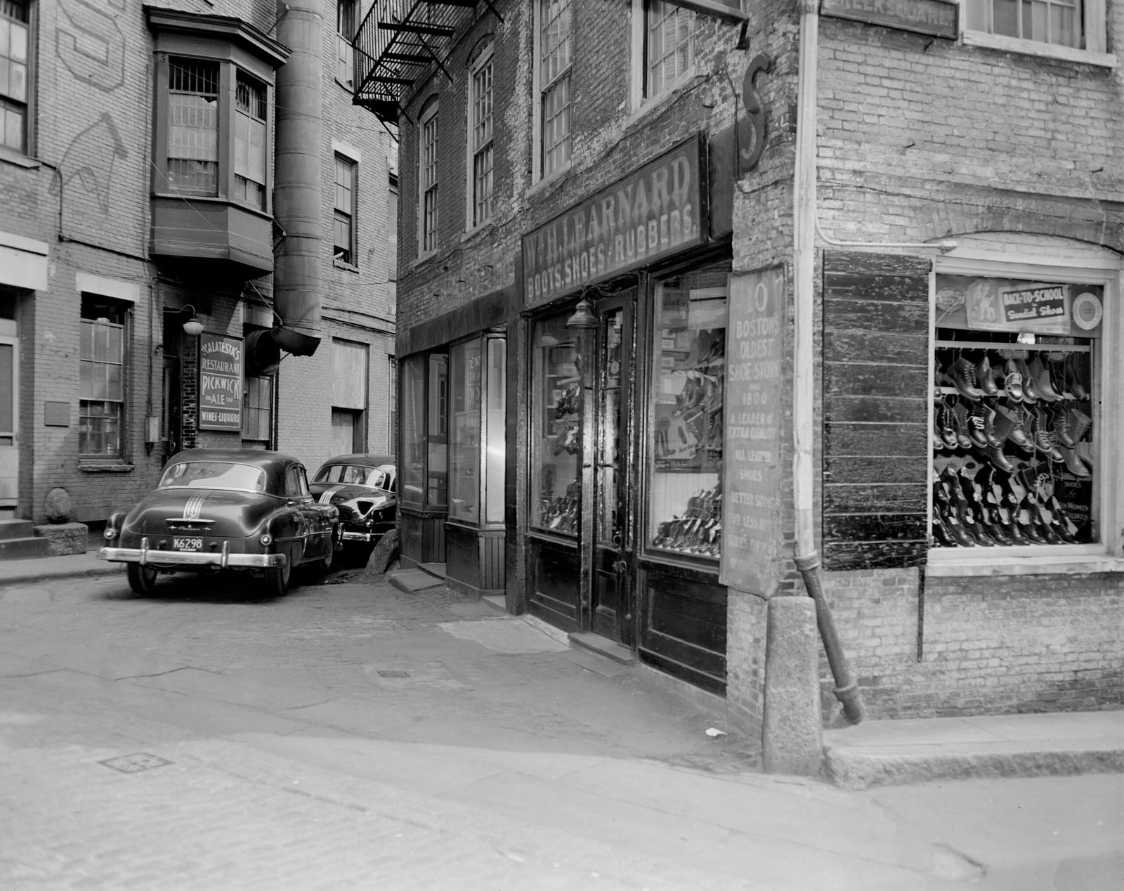 grayscale photo of cars parked beside building